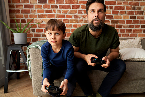 Front view of father and son playing video game at home