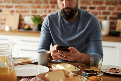Close up of man using mobile phone during breakfast