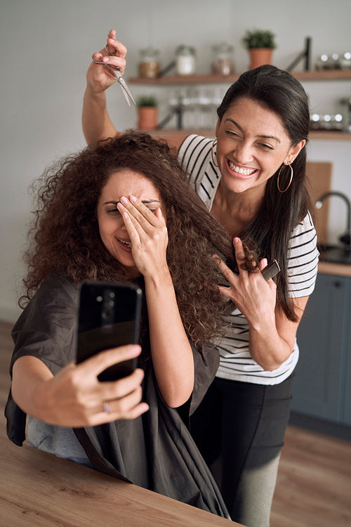 Happy women taking funny selfie while trimming their hair