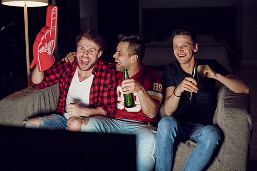 Men with foam hand and beer at football party