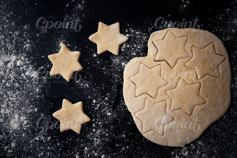 Top view of raw star shaped cookies over black background