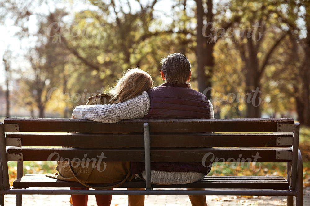 Senior caucasian couple sitting at the bench in park 