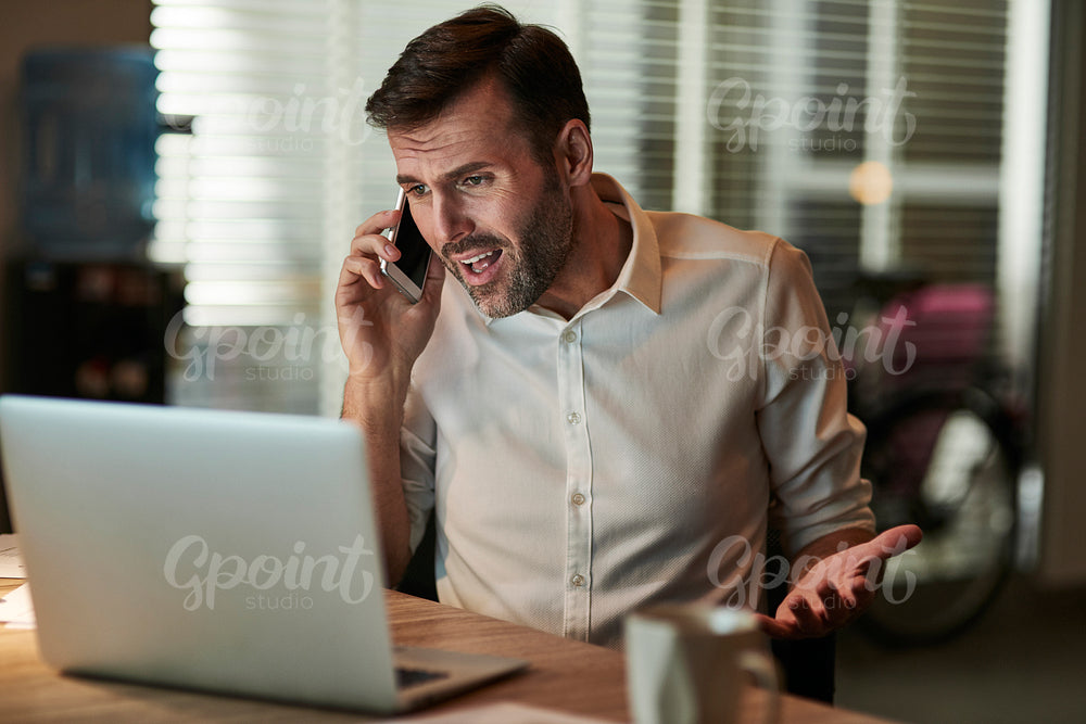 Angry businessman talking by mobile phone