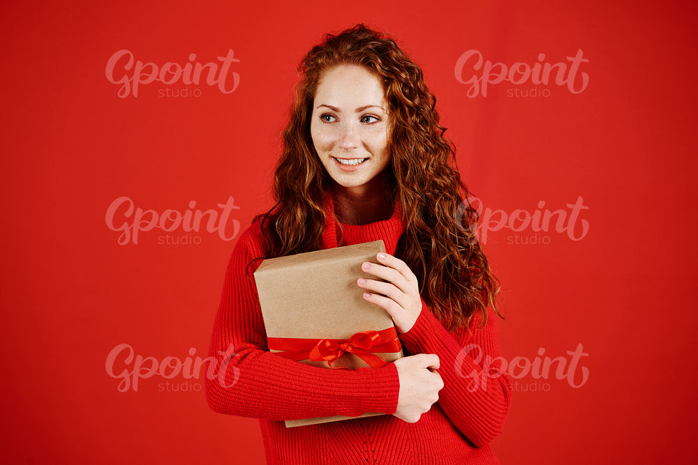 Smiling girl with christmas present looking at copy space