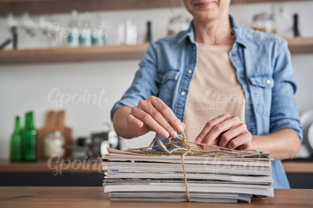 Woman preparing old newspapers for recycling