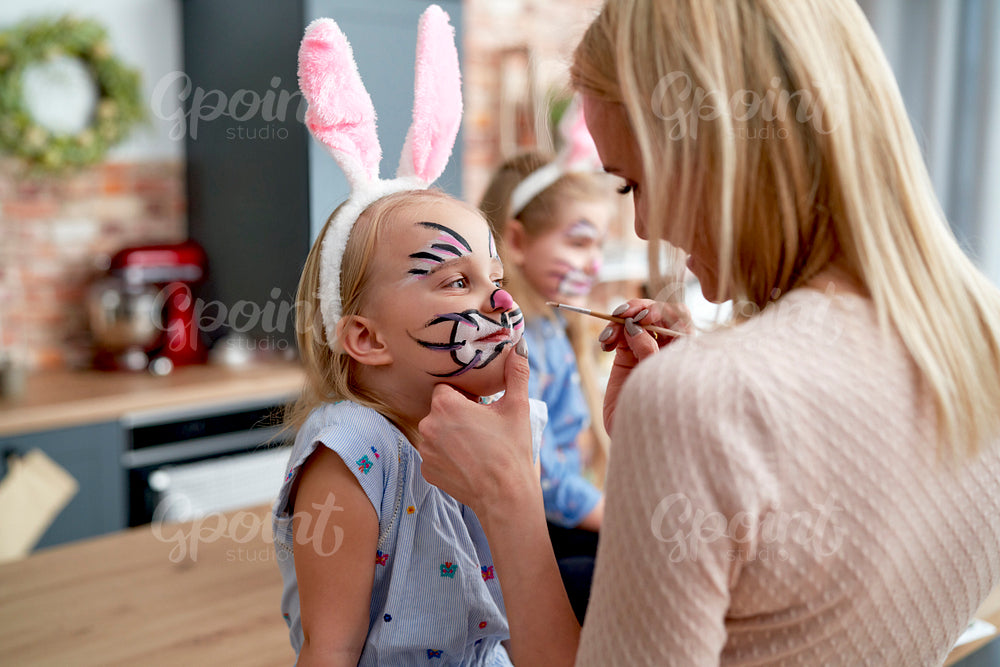 Mother painting Easter bunny on her daughter's face