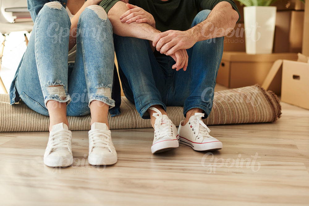 Low section of couple sitting on carpet