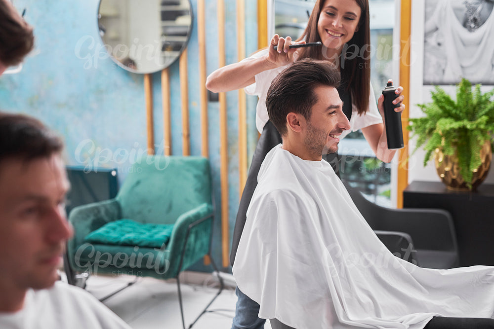 Hairstylist  is creating trendy hairstyle her male customer