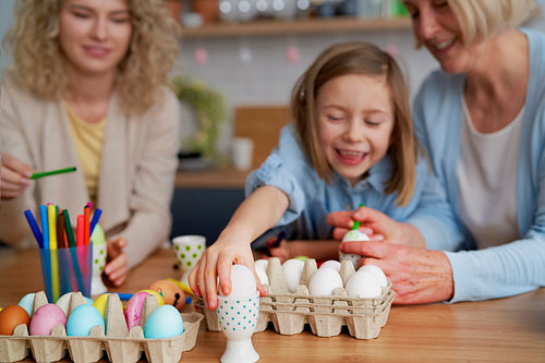 Happy family painting Easter eggs at home together