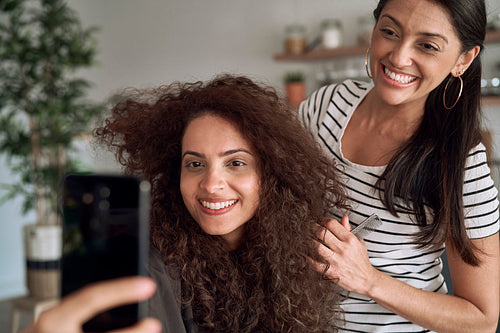 Happy women taking selfie during combing their hair