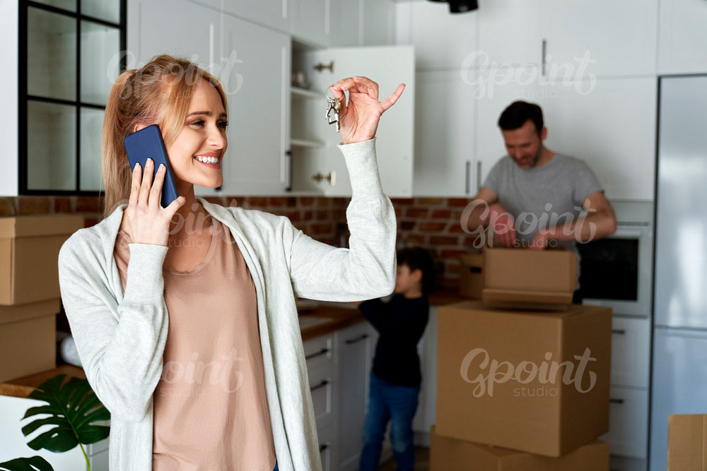 Happy woman calling and holding keys to a new house