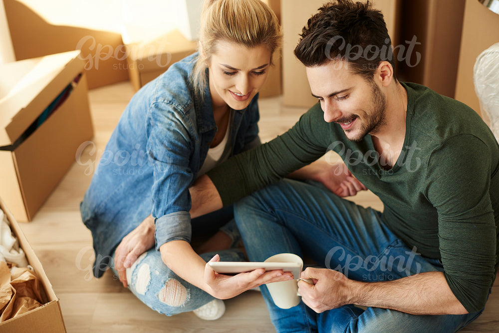 Couple around cardboard boxes with digital tablet