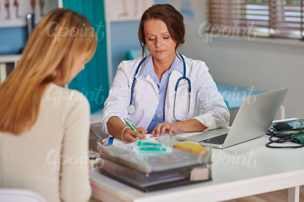 Doctor writing a prescription for her patient