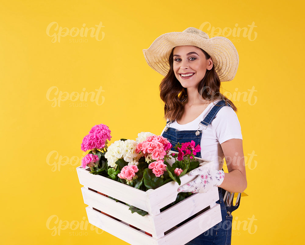 Smiling woman holding wooden crate with flowers