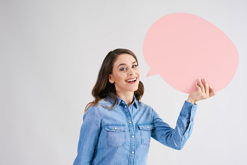 Smiling woman with empty speech bubble in studio shot
