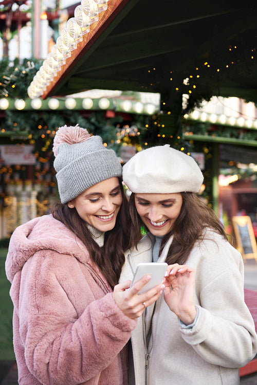 Two friends browsing mobile phone on a Christmas market