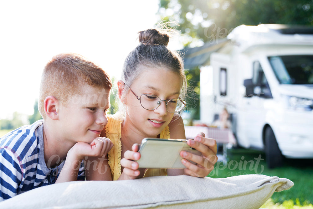 Children with mobile phone on camping holiday