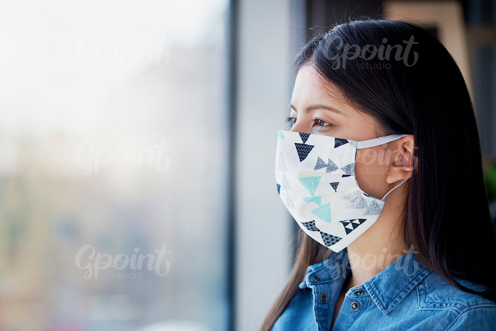 Asian woman in face mask looking through the window