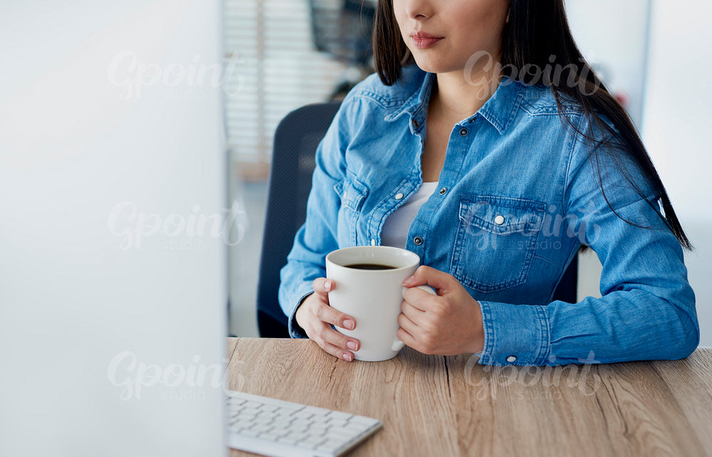 Unrecognizable woman at her desk with a cup of coffee