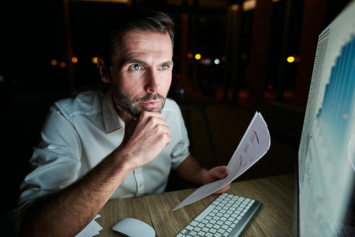 Focused man analyzing document at night