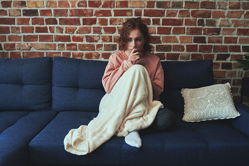 Depressed young caucasian woman sitting in silence on sofa