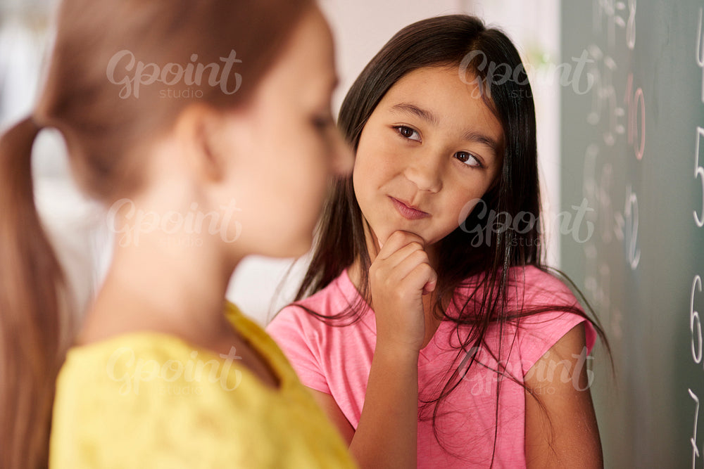 Girl with hand on chin looking at classmate