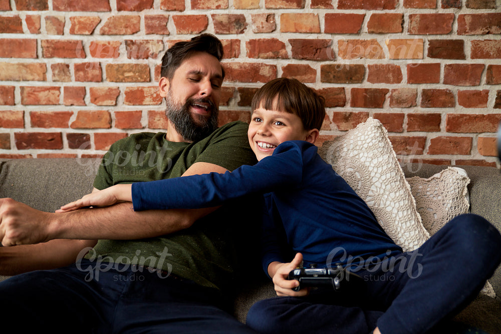Playful son  playing video game with father