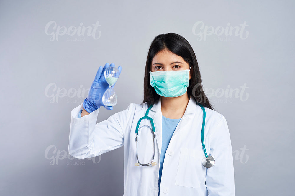 Female Asian doctor holding an hourglass