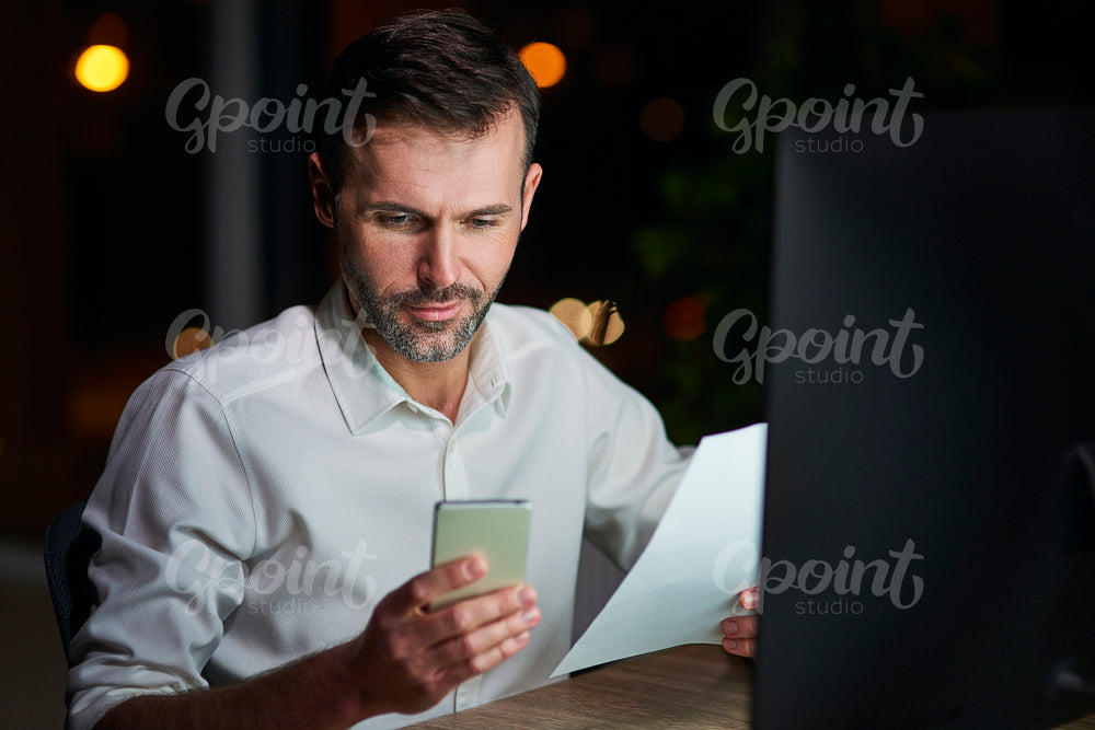 Mature businessman using mobile phone at night