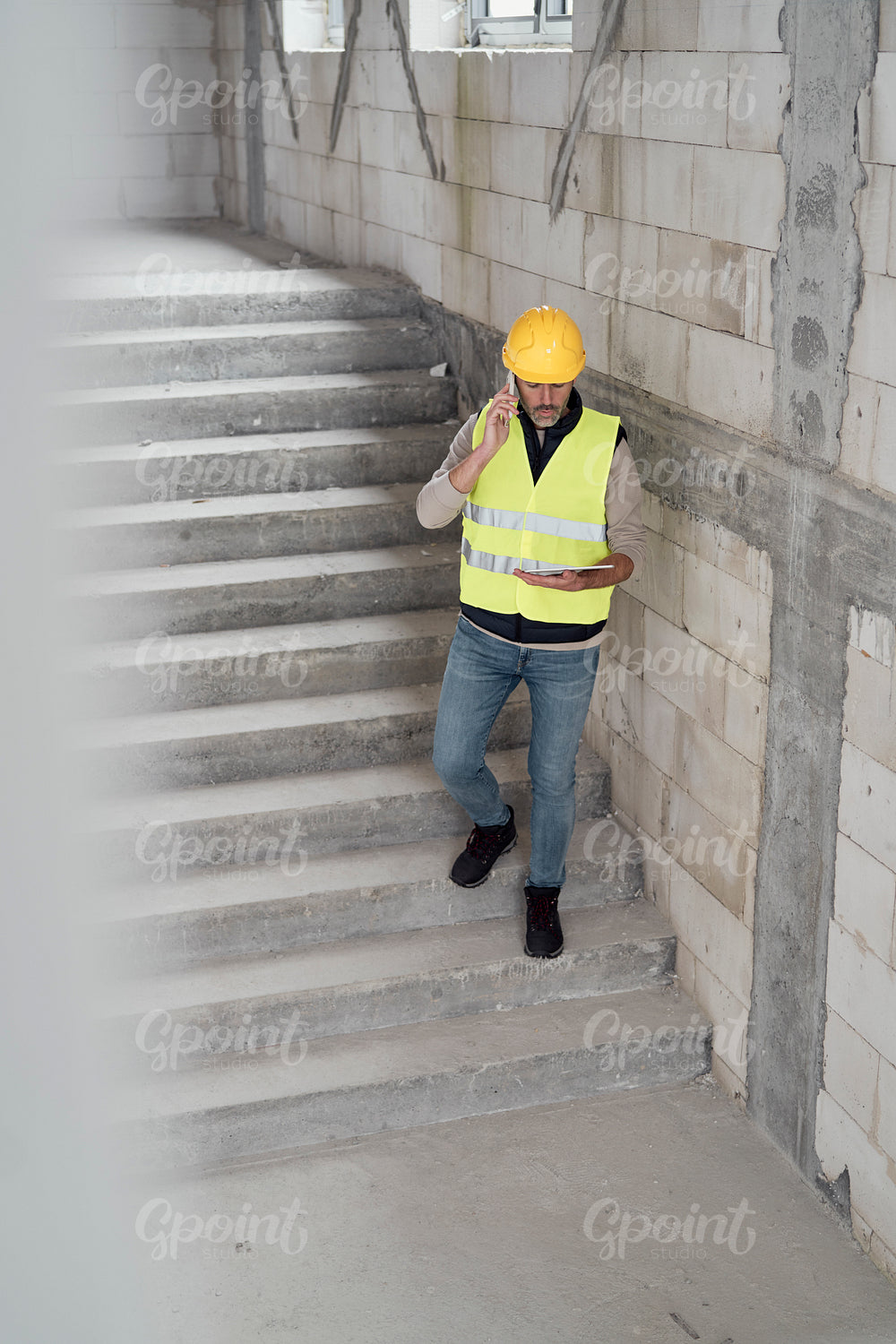 Caucasian engineer walking on stairs and browsing digital tablet on construction site