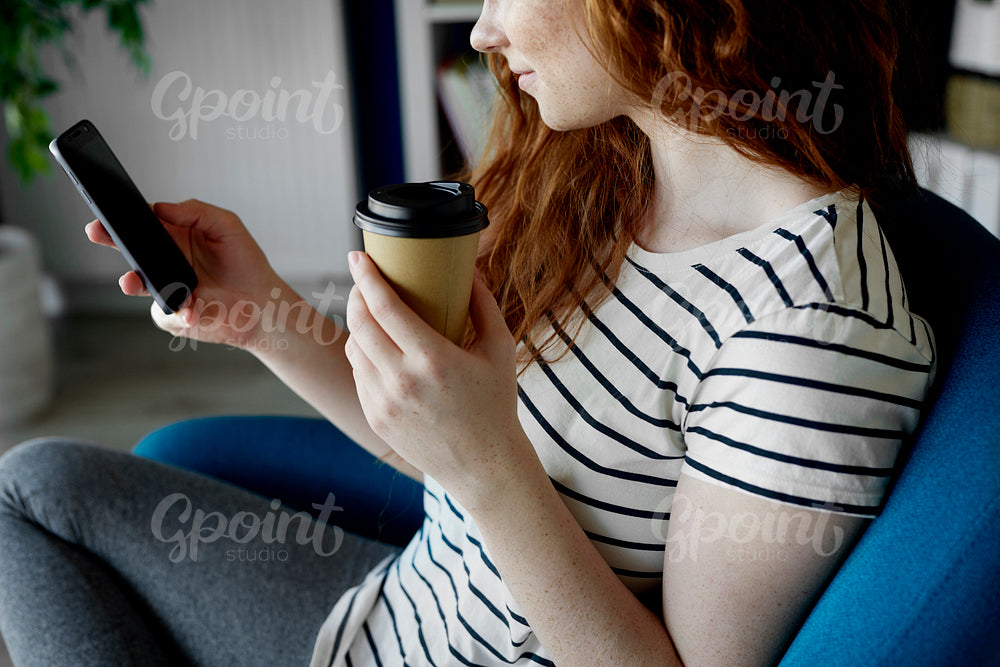 Woman sitting with a phone and cup of coffee