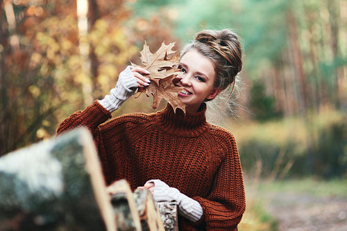 Portrait of young woman with autumnal leaves in forest