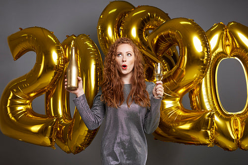 Screaming woman with golden balloon and champagne looking up