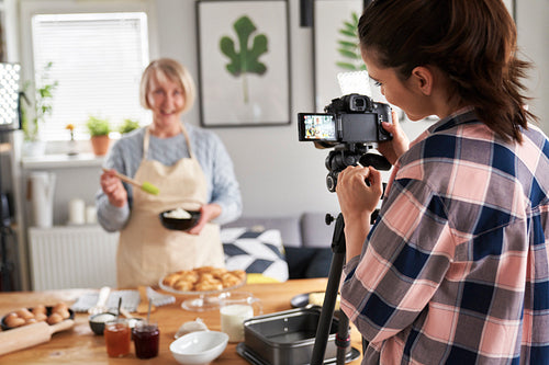 Daughter filming mother while cooking