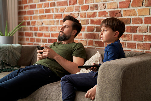 Father and son watches TV together at home