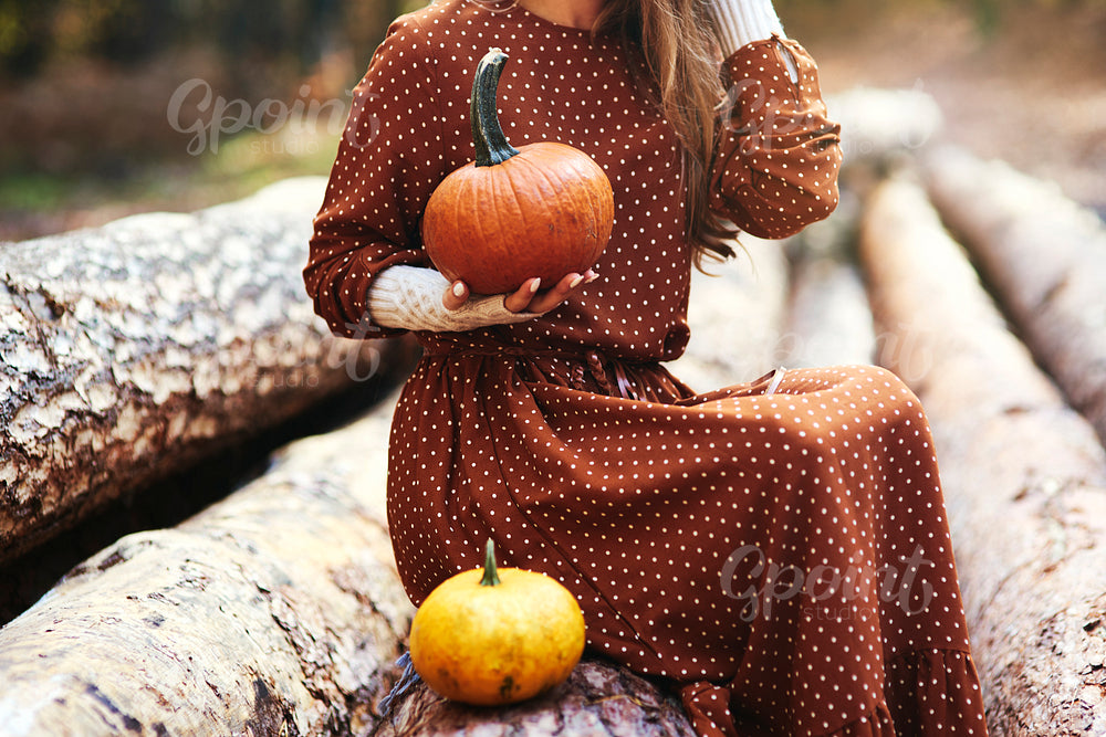 Close up of woman with pumpkin in autumn forest