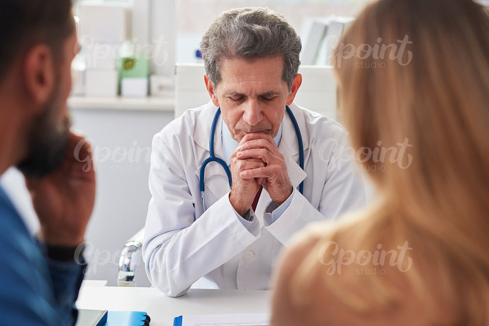 Senior doctor and young couple in doctor's office